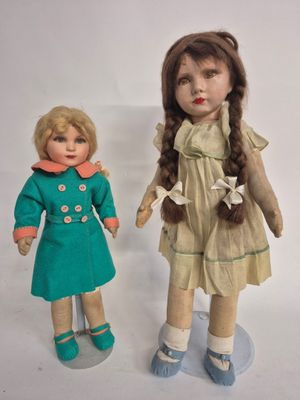 two dolls are standing next to each other on a white surface