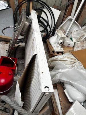 une borne d'incendie rouge posée au milieu d'un tas de vieilleries