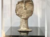 a glass display case with a stone head inside of it