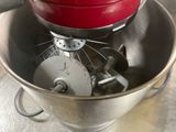 a red mixer in a metal bowl on a table
