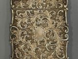 an antique silver cigarette case with a floral design on it