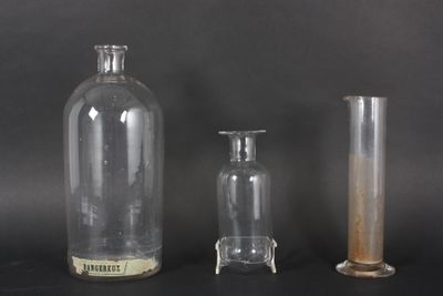 three glass vases and a glass bottle on a black surface