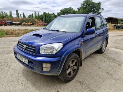 La voiture bleue est garée sur la terre battue du parking.