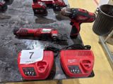 two cordless drillers and two batteries on a table