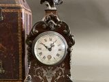 a small clock sitting next to a box with a bird on it
