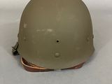 an army helmet is sitting on a white surface