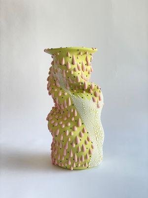 un vase vert orné de petites taches roses et jaunes