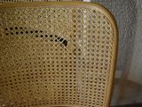 a cat sitting on a wicker chair in the corner of a room