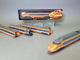 trois trains miniatures assis l'un à côté de l'autre sur une table