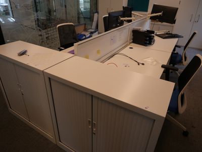 une photo d'un espace de travail en open space comprenant deux bureaux et une chaise