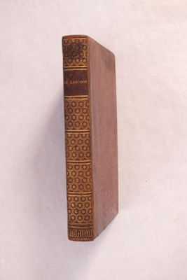 un livre marron posé sur une surface blanche, avec un fond blanc