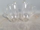 pair of clear glass vases sitting on top of a cement floor