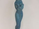 une statue bleue représentant une femme debout sur une table blanche