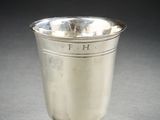 an antique silver cup on a pedestal on a gray surface