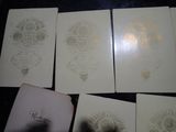 four cards with gold foil on them sitting on top of a table