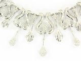 necklace made of silver colored metal with a design of swirls and drops