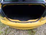 a yellow car with its trunk open in the grass