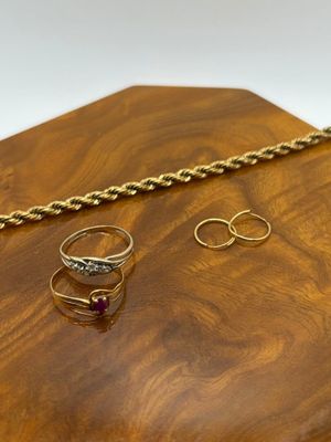 two gold rings and a gold chain on a wooden tray