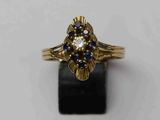gros plan d'une bague en or avec des pierres bleues et blanches