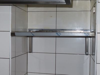 une photo d'une cuisine avec du carrelage blanc et une étagère en inox