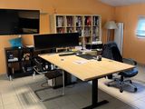 a room with a desk, chairs, and a television in it