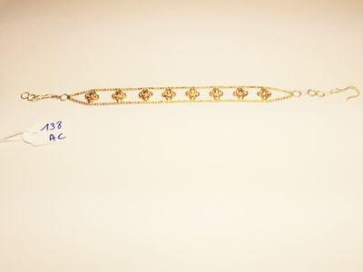 a close up of a gold bracelet on a white surface