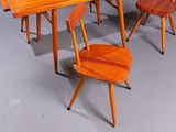 several wooden chairs and a table in a room with a gray floor