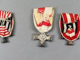 three medals are displayed on a gray surface with red and white stripes