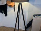 a lamp that is on a tripod next to a coat rack