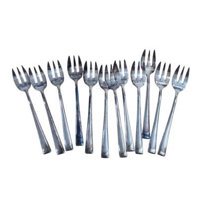 six forks are arranged in a row on a white surface