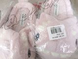 three pink teddy bears wrapped in plastic bags on a couch