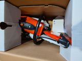 an orange and black chainsaw in a cardboard box