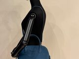 the mannequin is holding a blue handbag on a mannequin stand