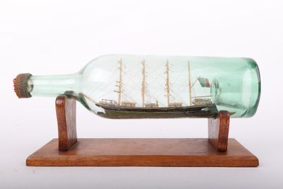 une bouteille en verre contenant un bateau sur un support en bois