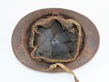 an old rusty helmet on a white surface with a brown strap