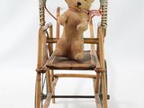 a teddy bear sitting in a rocking chair on a white background