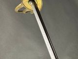 a close up of a sword on a gray surface with clouds in the background