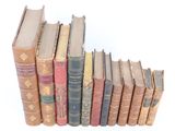 several old books are lined up in a row on a white surface