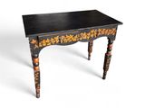une image représentant une petite table avec un plateau noir orné de fleurs dorées