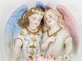 two figurines of angels on a cake on a table