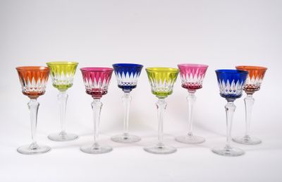 six verres à vin colorés alignés en rang sur une surface blanche