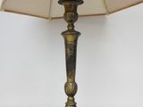 an antique brass table lamp with a beige shade on a white background