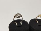 two gold and silver rings sitting on top of a black ring holder