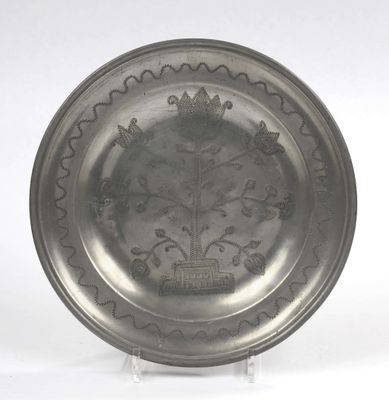 a silver plate with a design on it on a stand