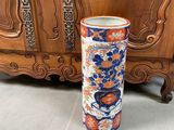 un grand vase posé par terre à côté d'un meuble