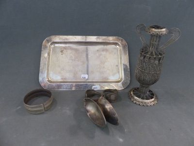 un plateau en argent et une paire de chaussures à côté d'un vase en argent