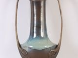 a vase that is sitting on a stand on a white surface