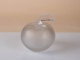 a glass apple with a leaf on it sitting on a table