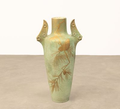 un vase vert orné de pommes de pin, posé sur une table