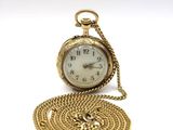 a small gold pocket watch with a chain around it